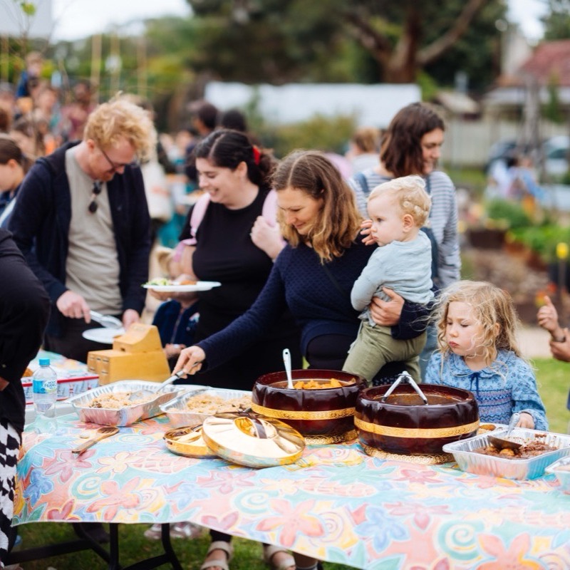 Children and parents crowding around the lunch table with big bowls of food